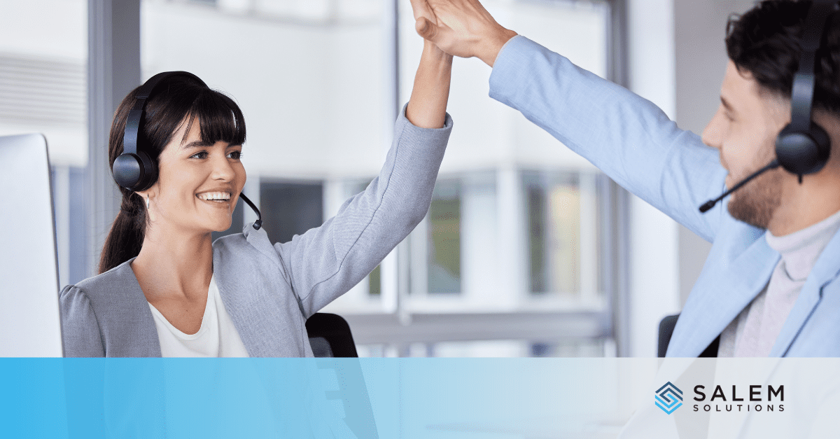 A woman in a headset and a man in a suit high-five each other.