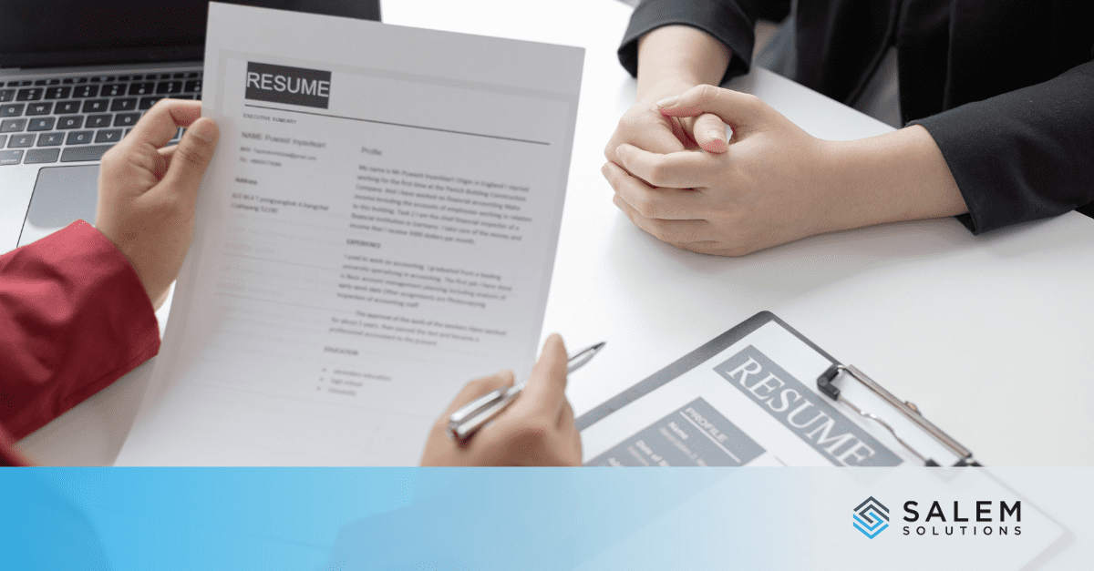 Two people sitting at a table looking over a resume.