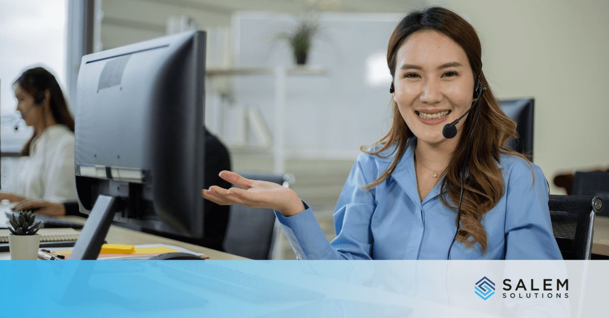 A woman wearing a headset sitting in front of a computer.
