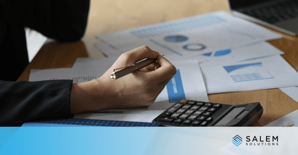 A person writing on a piece of paper with a calculator.