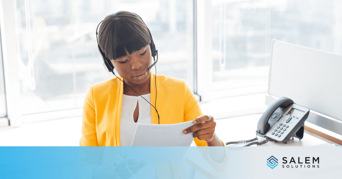 A woman with headphones is looking at a piece of paper.