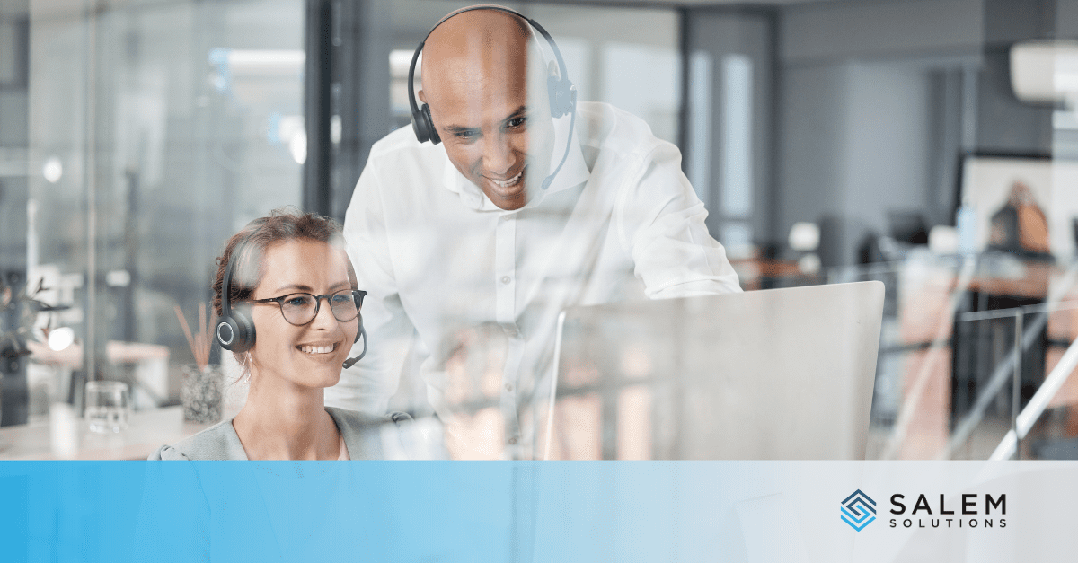A man and a woman wearing headsets looking at a laptop.