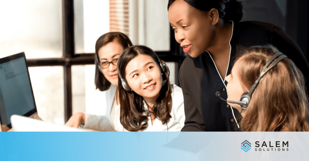 Three women in front of a computer, discussing contact center leadership and coaching strategies for developing team leads.