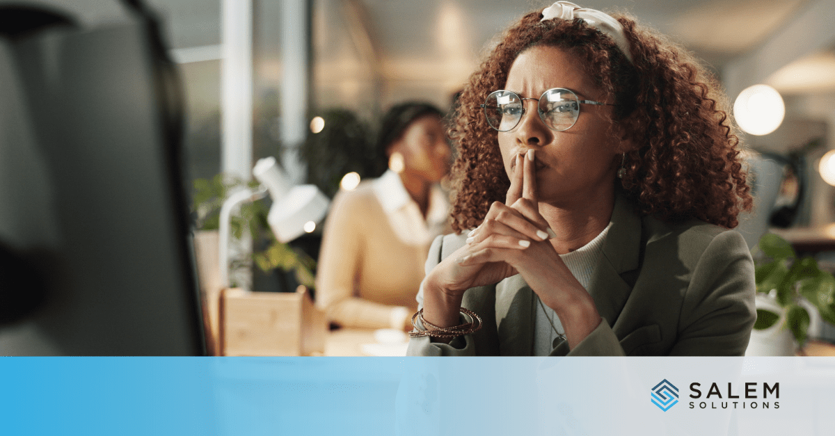 A woman frowning at a computer screen, thinking about early signs of workplace disengagement.